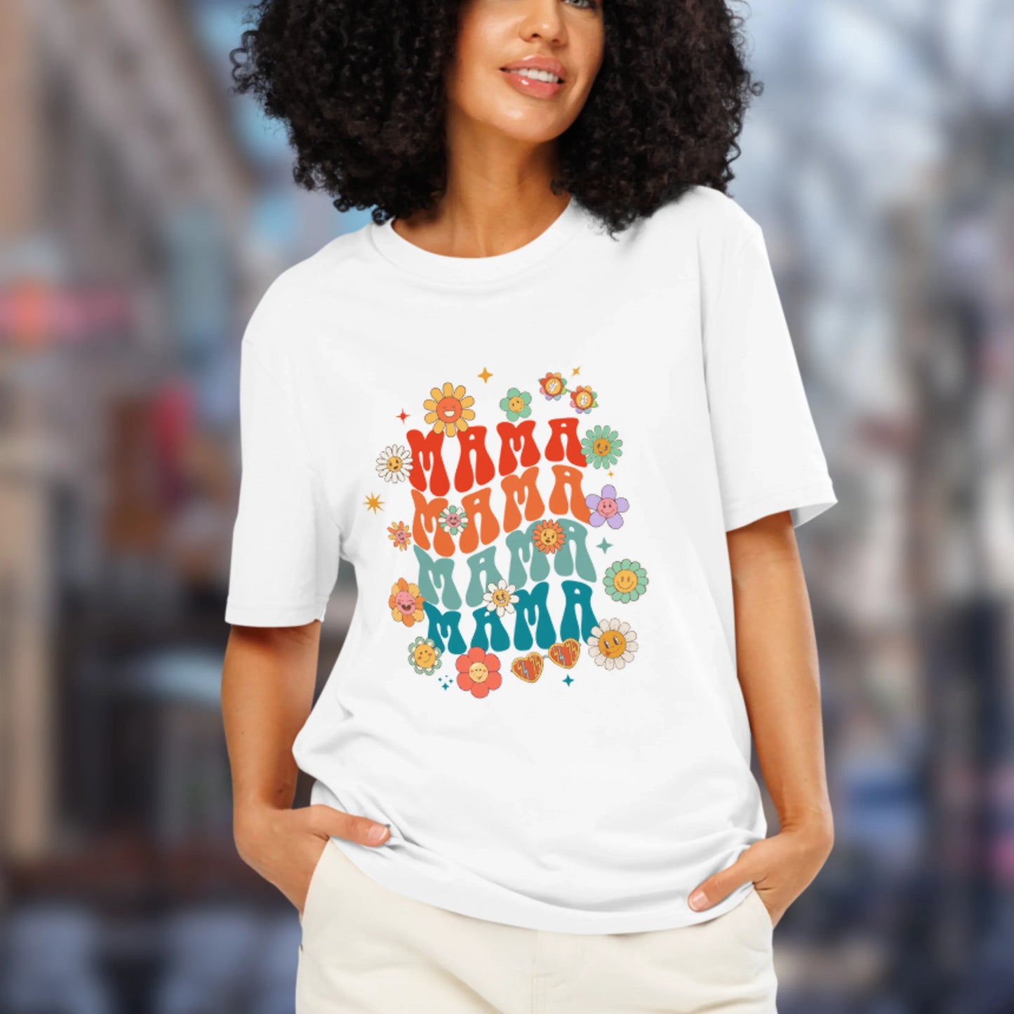 Woman wearing a white t-shirt with colorful 'MAMA' text design in an urban setting