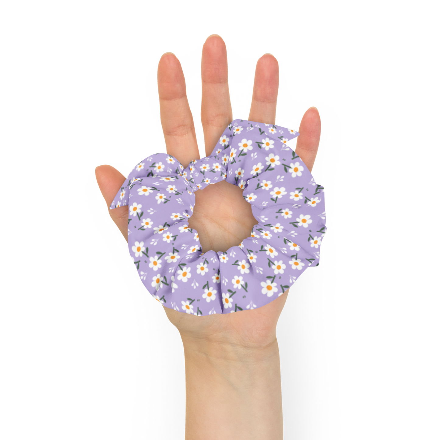 Hand holding a purple floral scrunchie against a white background