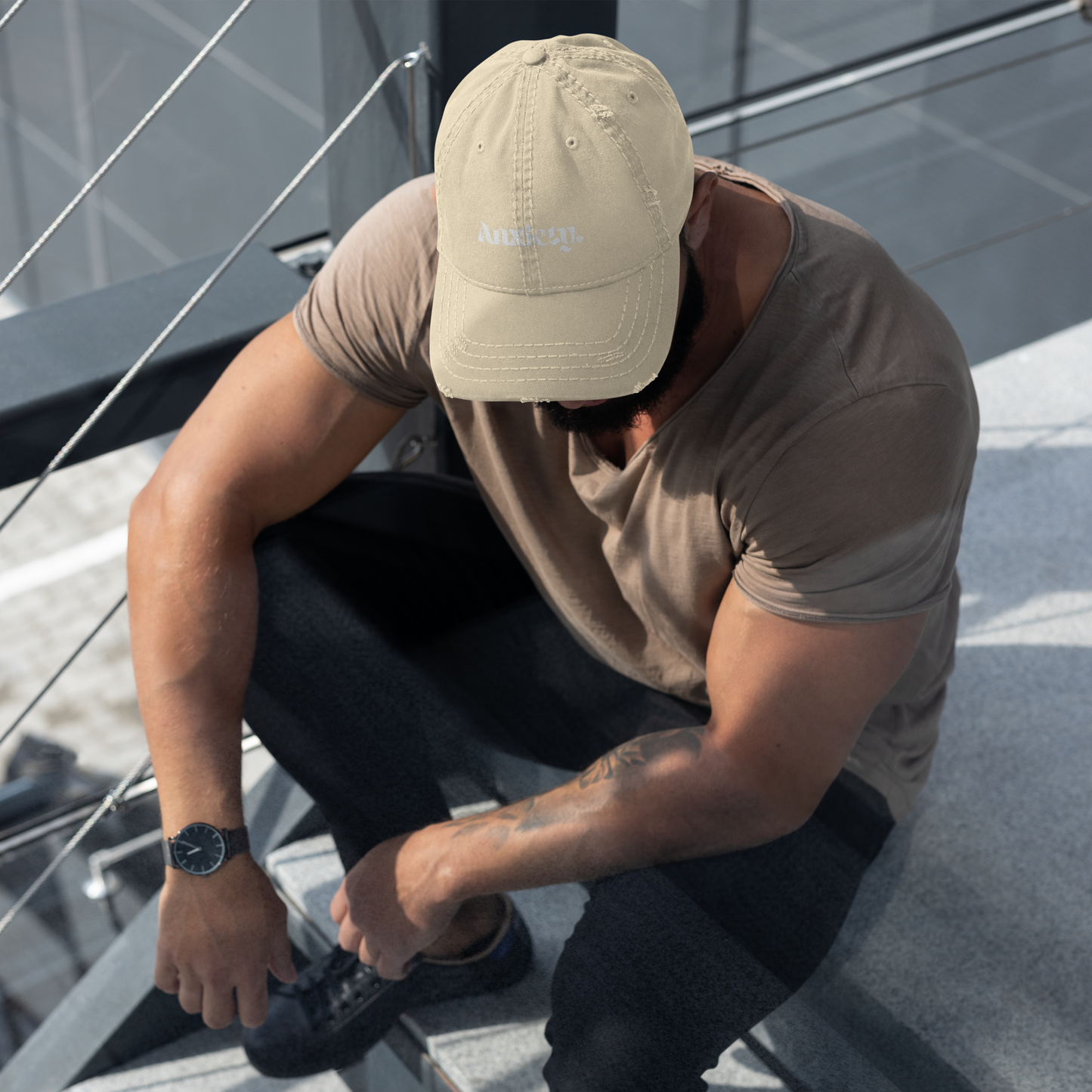 Man sitting on a boat wearing a beige cap and brown shirt, tying his shoe.
