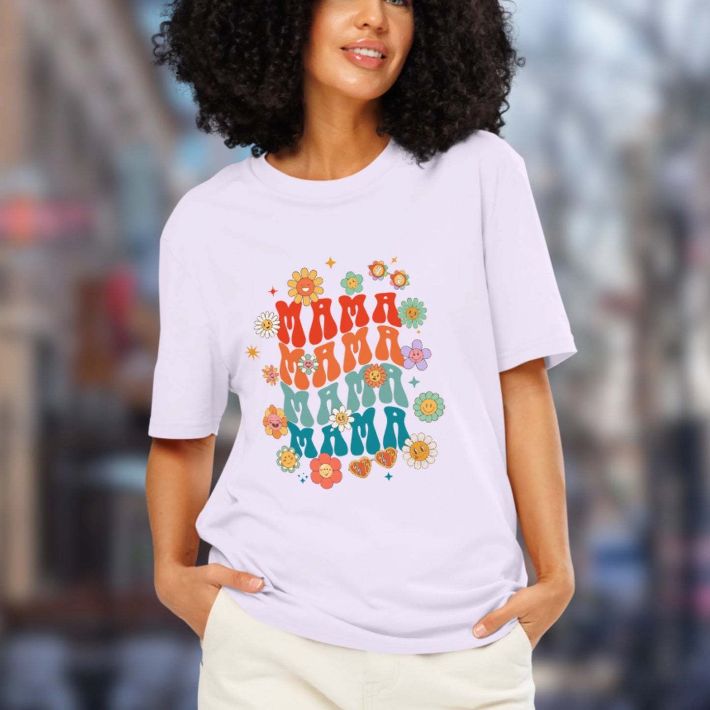 Woman wearing a lilac t-shirt with 'MAMA' text and floral designs in an urban setting