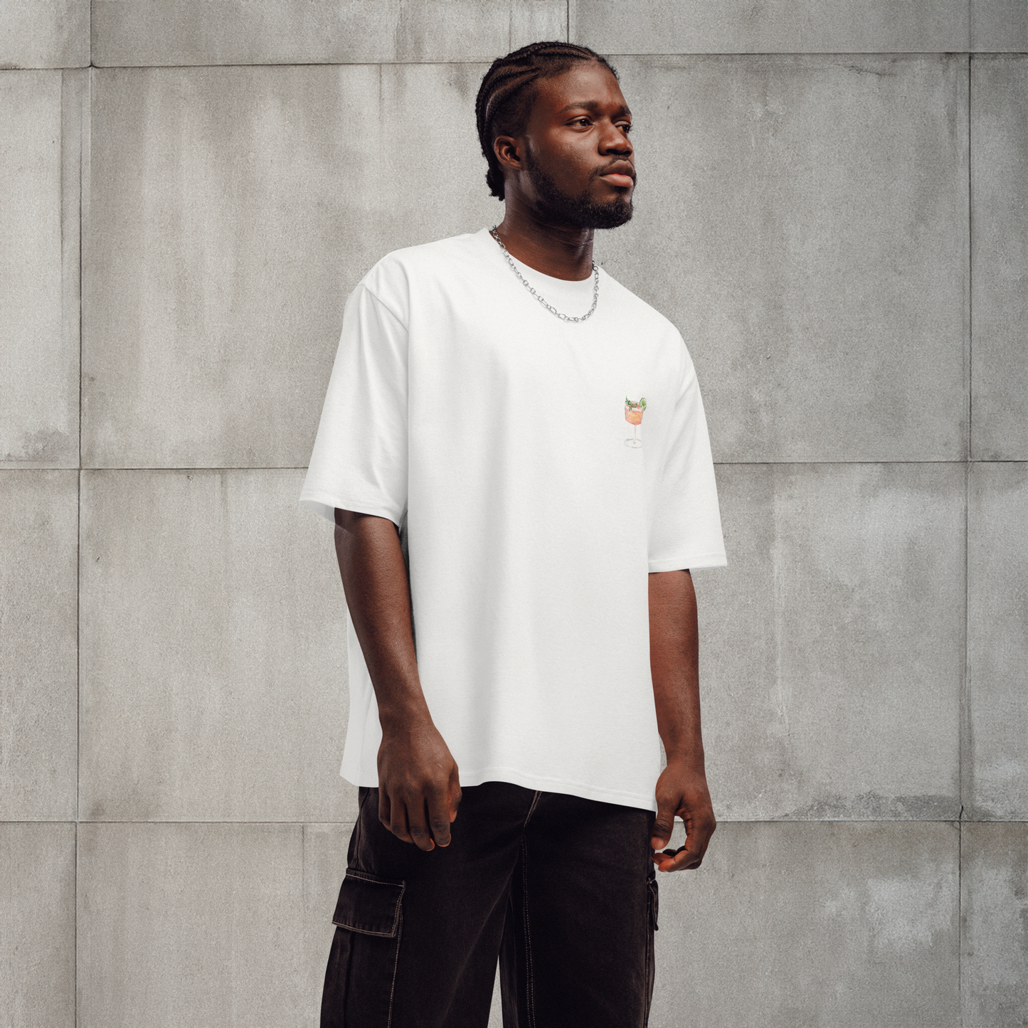Man wearing a white t-shirt with a small logo against a gray concrete wall