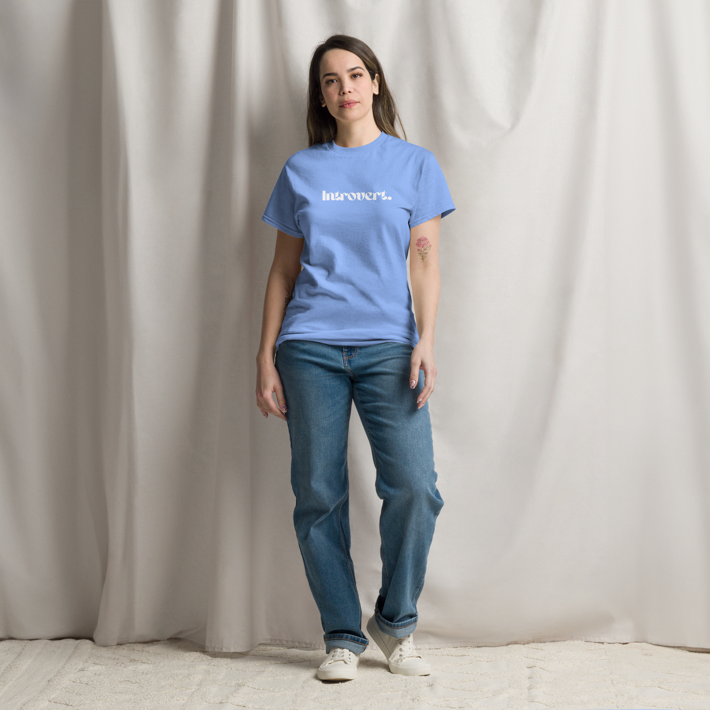 Person wearing a blue t-shirt with text and jeans against a plain background