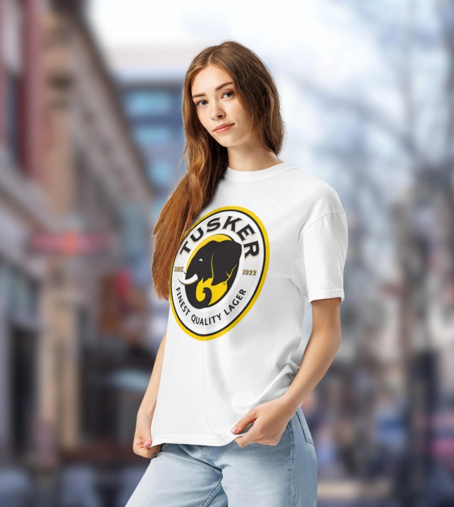 Woman wearing a white t-shirt with a yellow and black logo in an urban setting