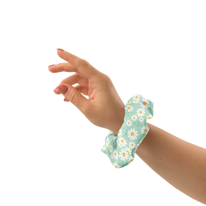 Hand wearing a green floral scrunchie on a white background
