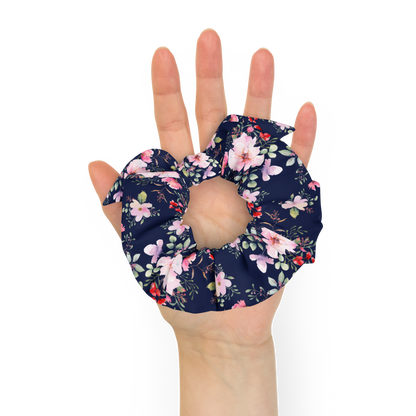 Hand holding a floral scrunchie against a white background