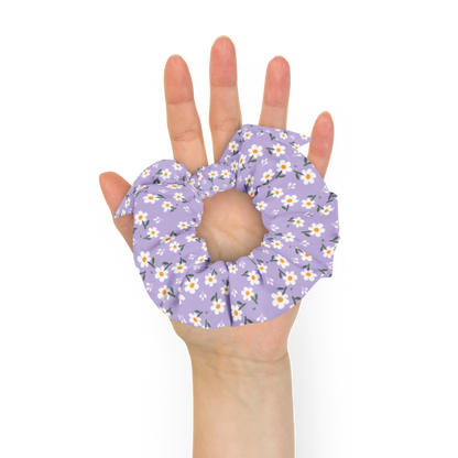 Hand holding a purple floral scrunchie against a white background