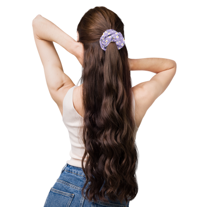 Woman with long wavy hair tied back with a scrunchie on a white background