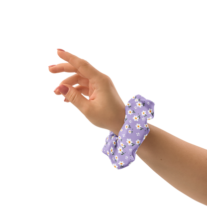 Hand wearing a purple floral scrunchie on a white background
