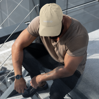 Man sitting on a boat wearing a beige cap and brown shirt, tying his shoe.