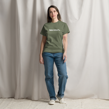 Person wearing a green t-shirt with text and blue jeans against a plain background