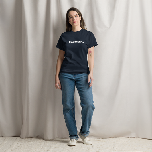 Person wearing a navy blue t-shirt with text and blue jeans against a plain background
