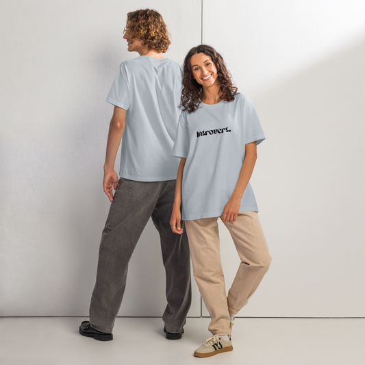 Two people wearing light blue t-shirts with a brand logo, standing against a white wall.