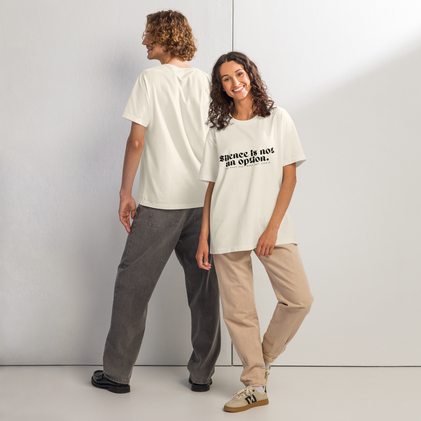 Two people wearing white t-shirts with text, standing side by side against a plain background.